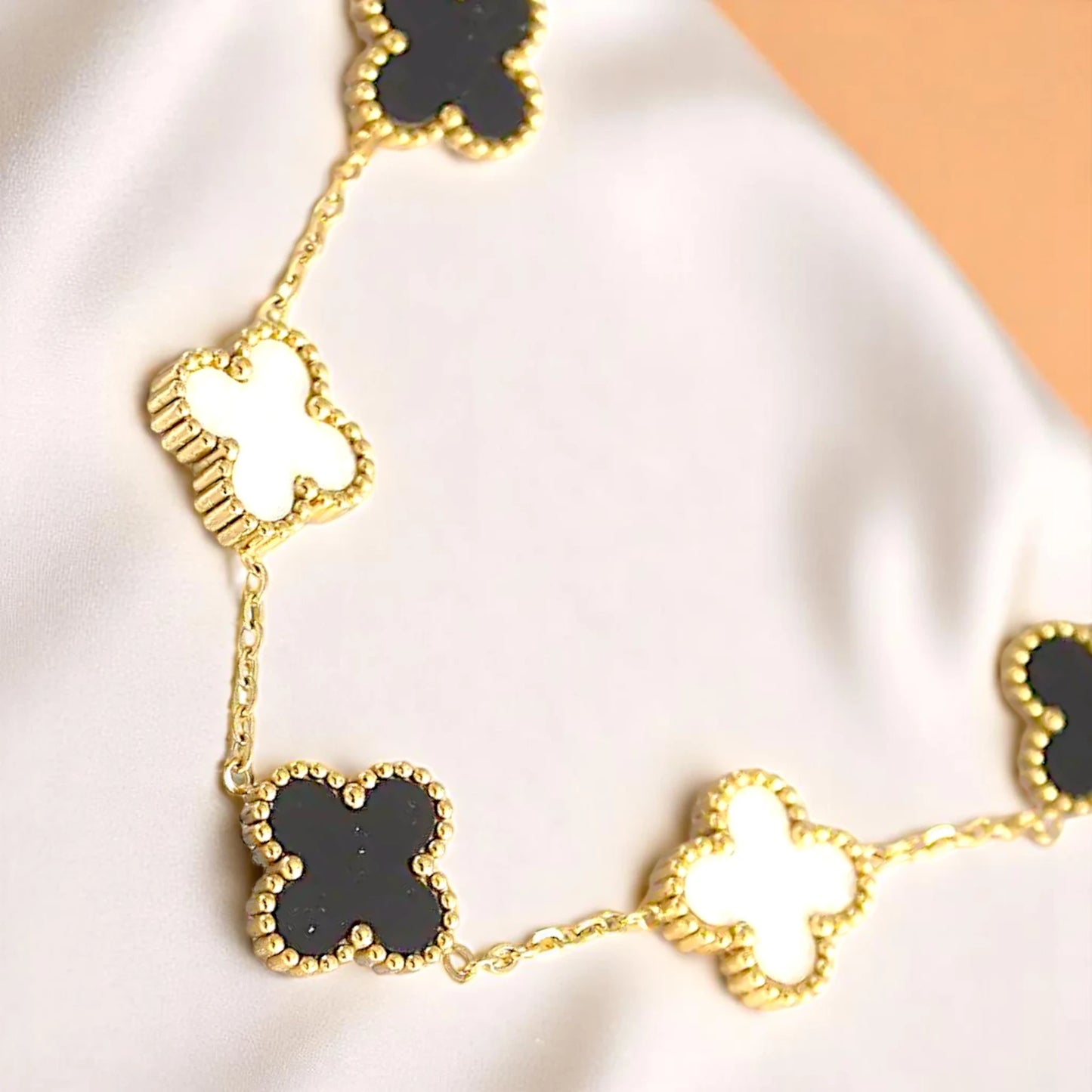 Bracelet on white draped nylon cloth with a peach color gradient in the background.