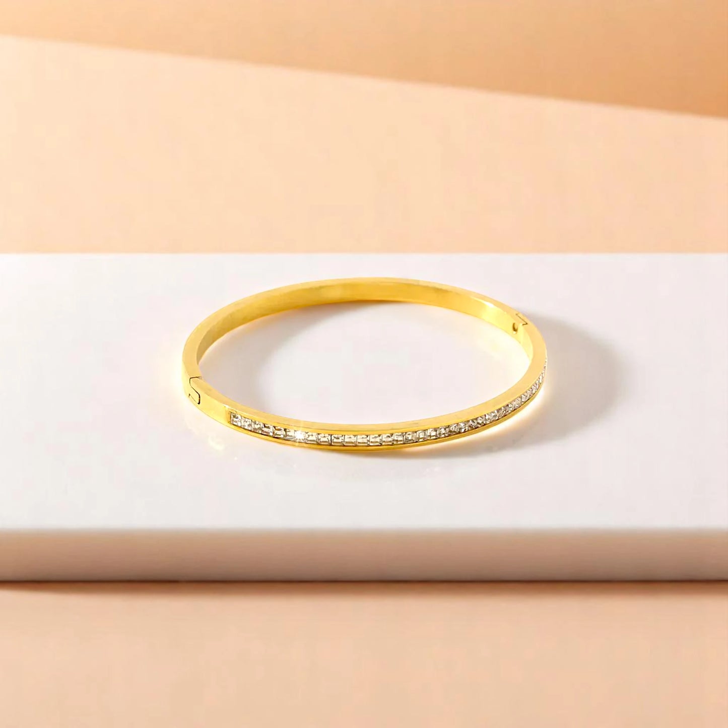 Bracelet on geometric prop with peach color gradient in the background.