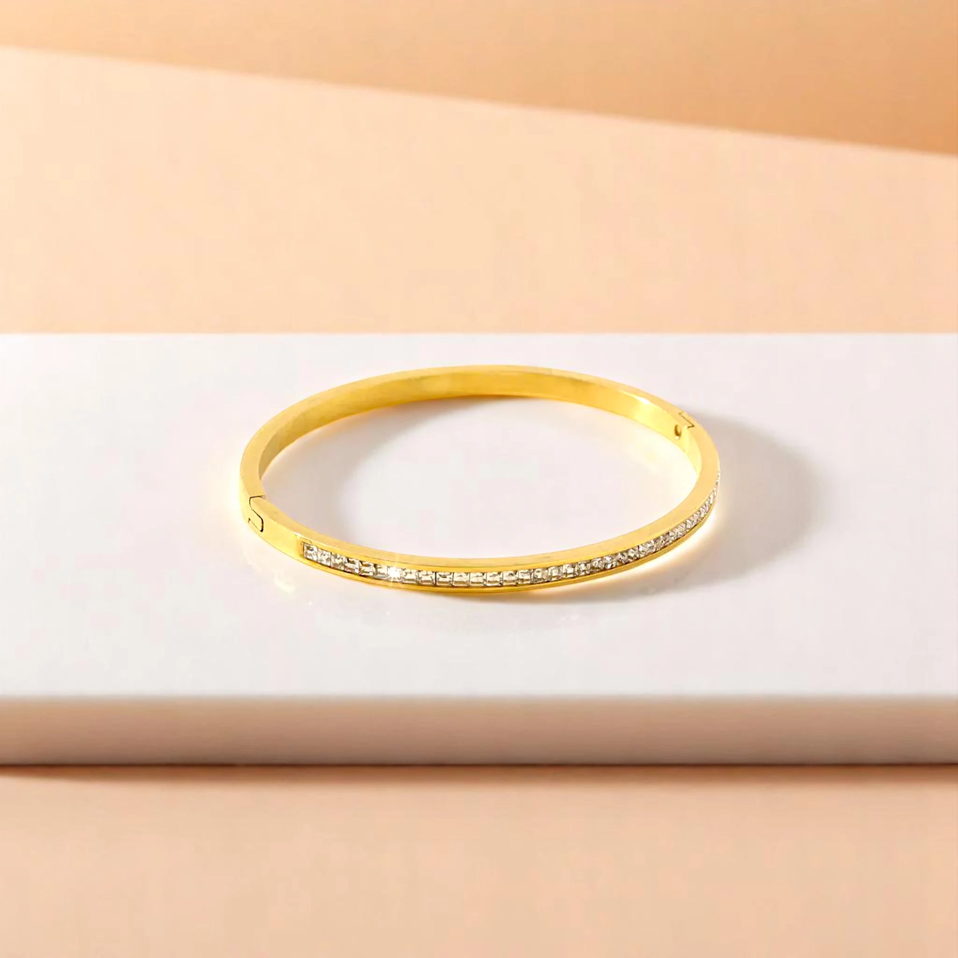 Bracelet on geometric prop with peach color gradient in the background.