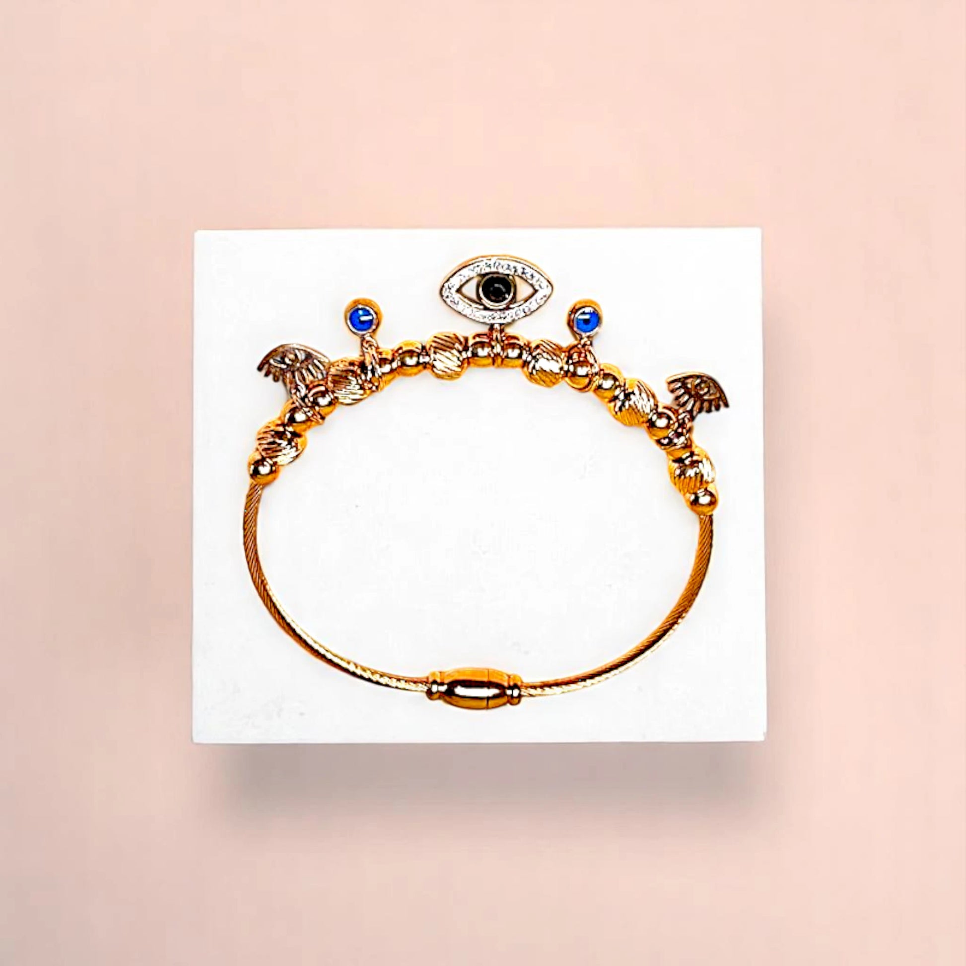 Bracelet on geometric prop with peach color gradient in the background.