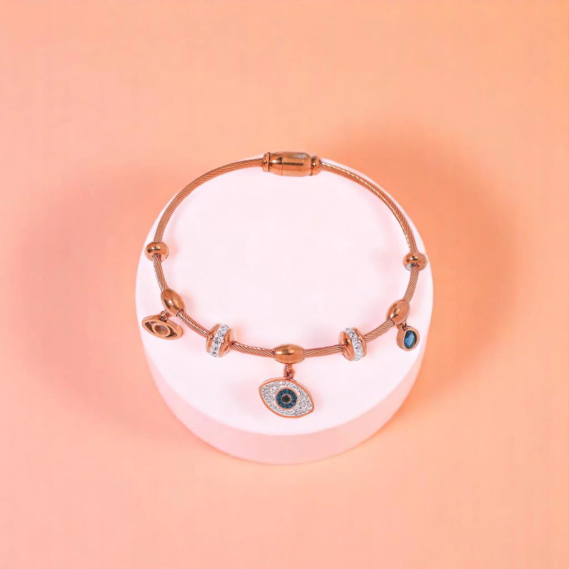 Bracelet on geometric prop with peach color gradient in the background.