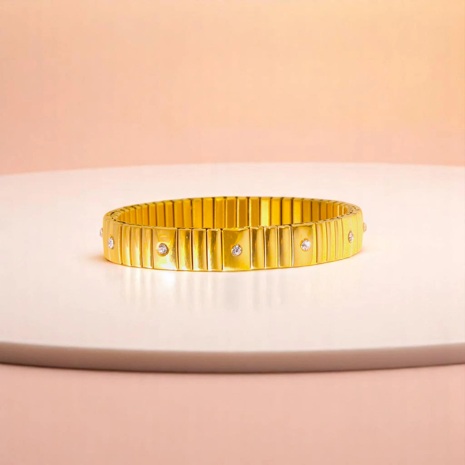 Bracelet on geometric prop with peach color gradient in the background.
