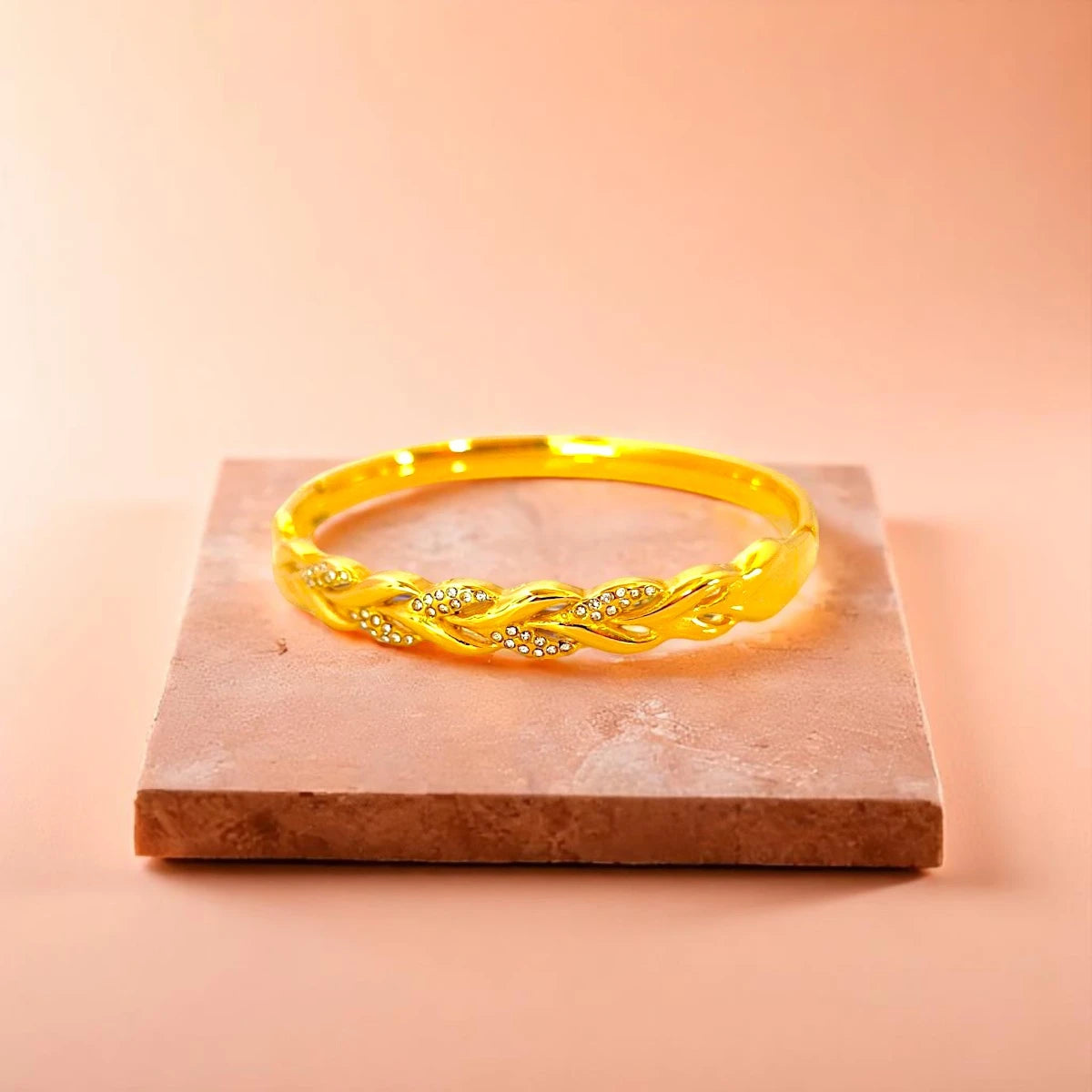 Bracelet displayed on a light-colored travertine stone slab with a peach-colored gradient in the background.