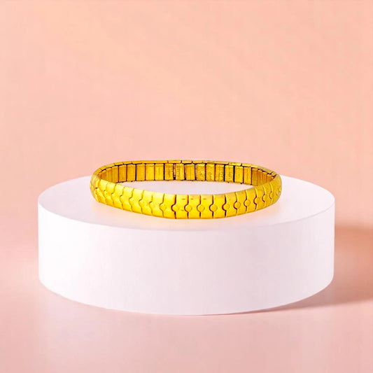 Bracelet on geometric prop with peach color gradient in the background.