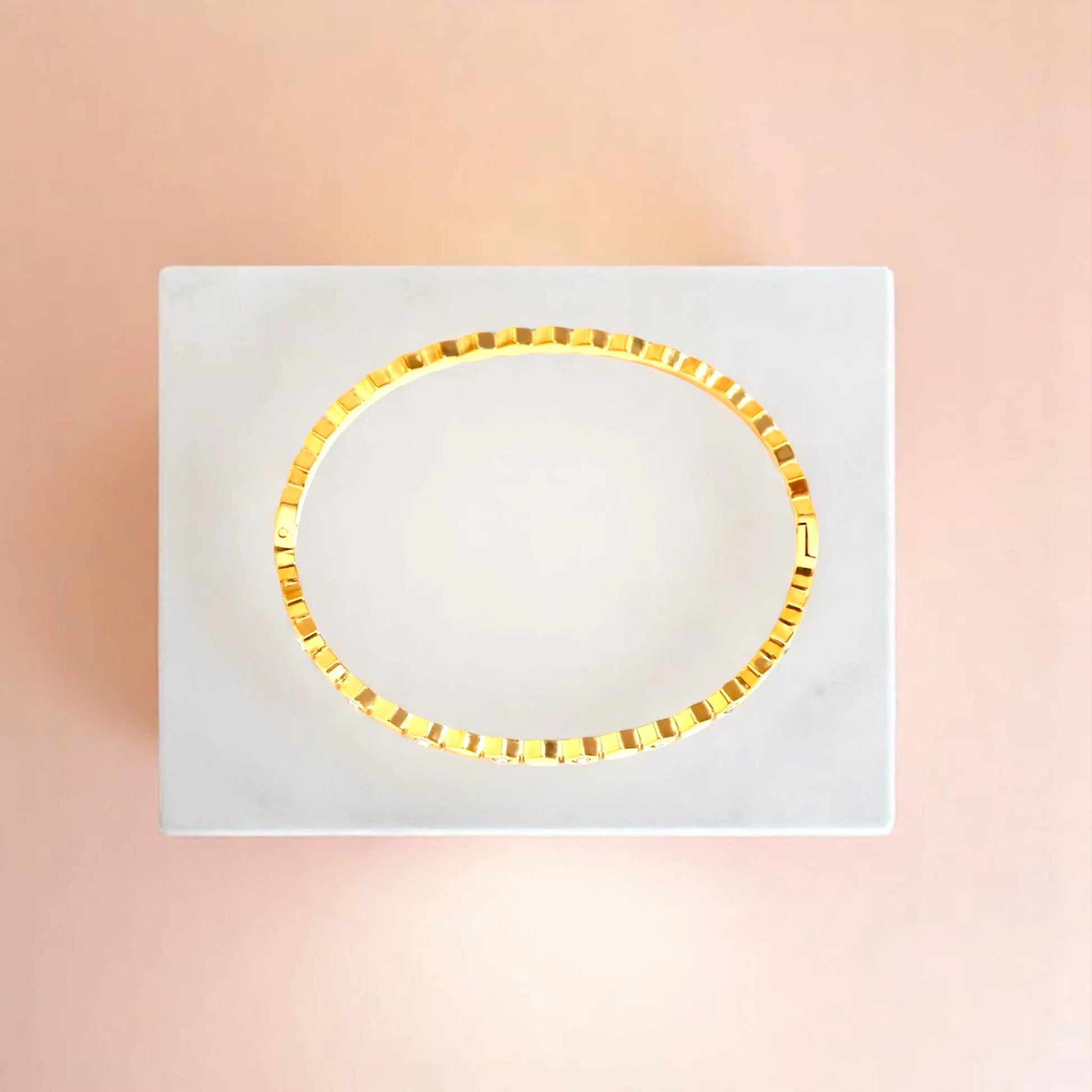 Bracelet on geometric prop with peach color gradient in the background.