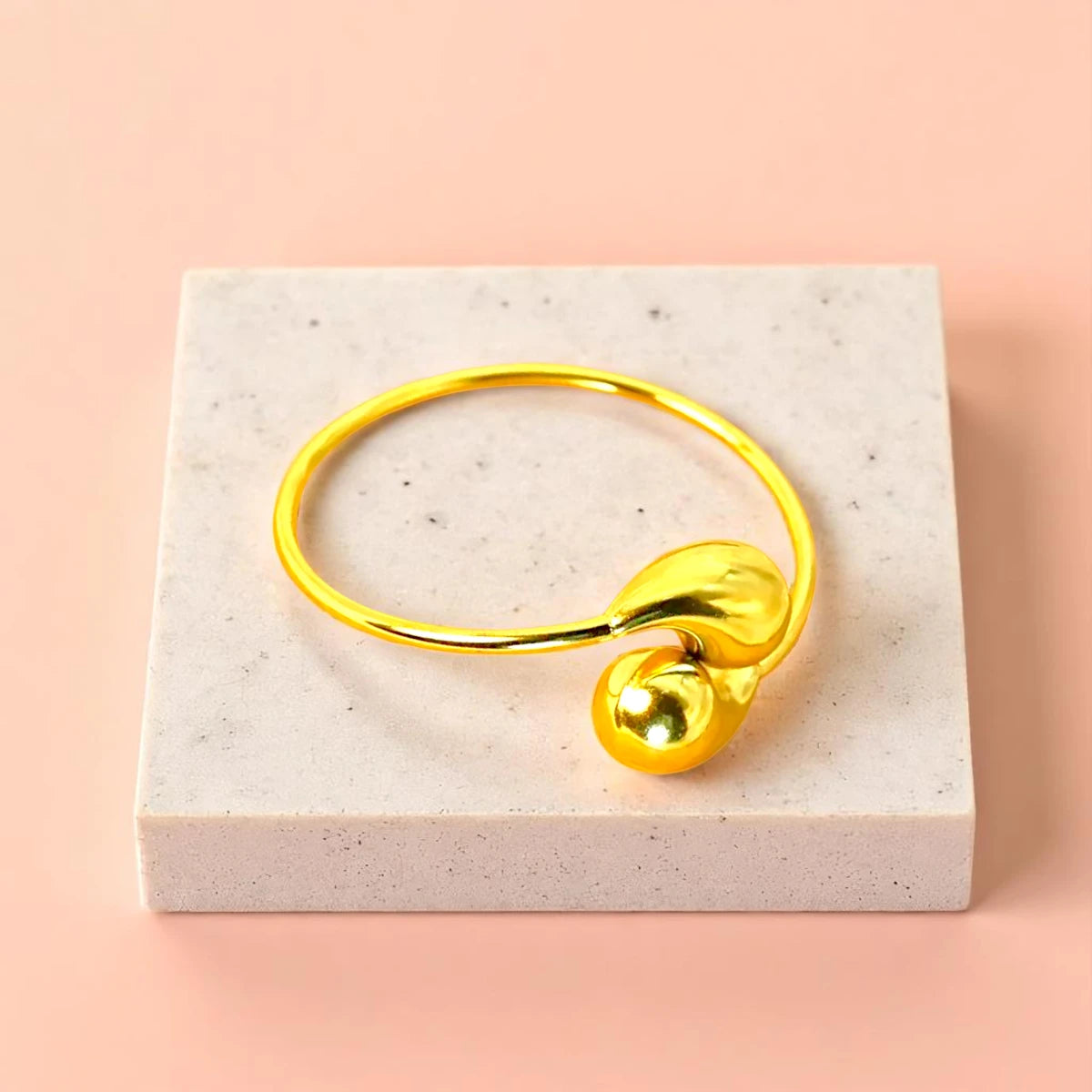 Bracelet displayed on a light-colored travertine stone slab with a peach-colored gradient in the background.