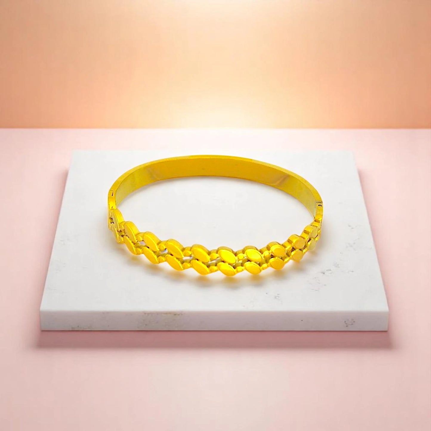 Bracelet on geometric prop with peach color gradient in the background.