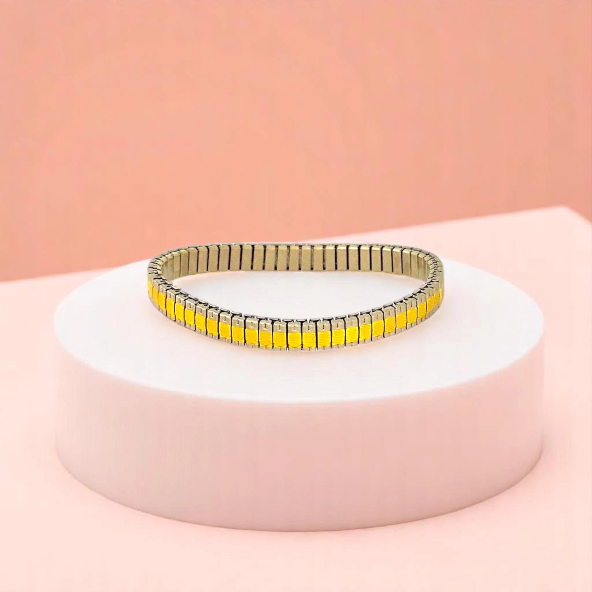 Bracelet on geometric prop with peach color gradient in the background.