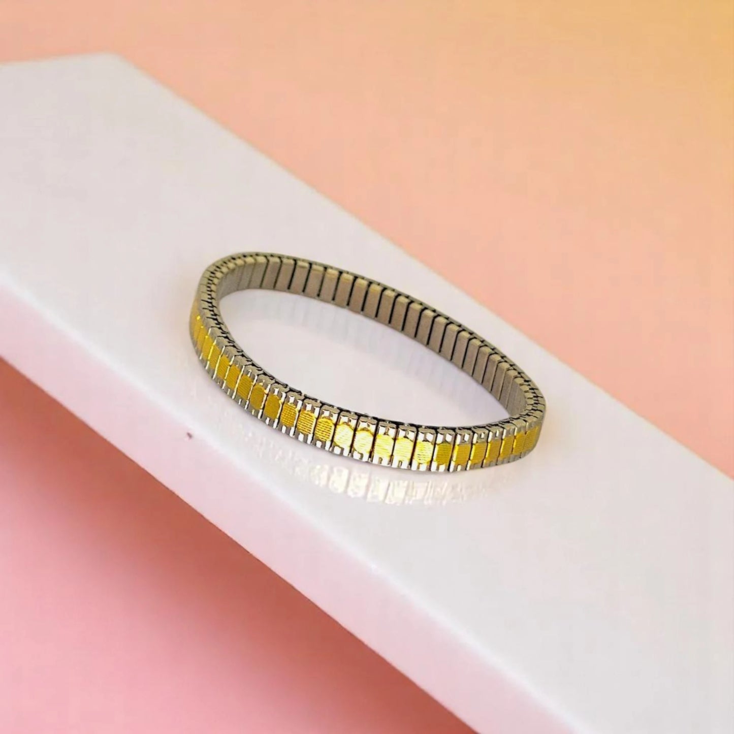 Bracelet on geometric prop with peach color gradient in the background.