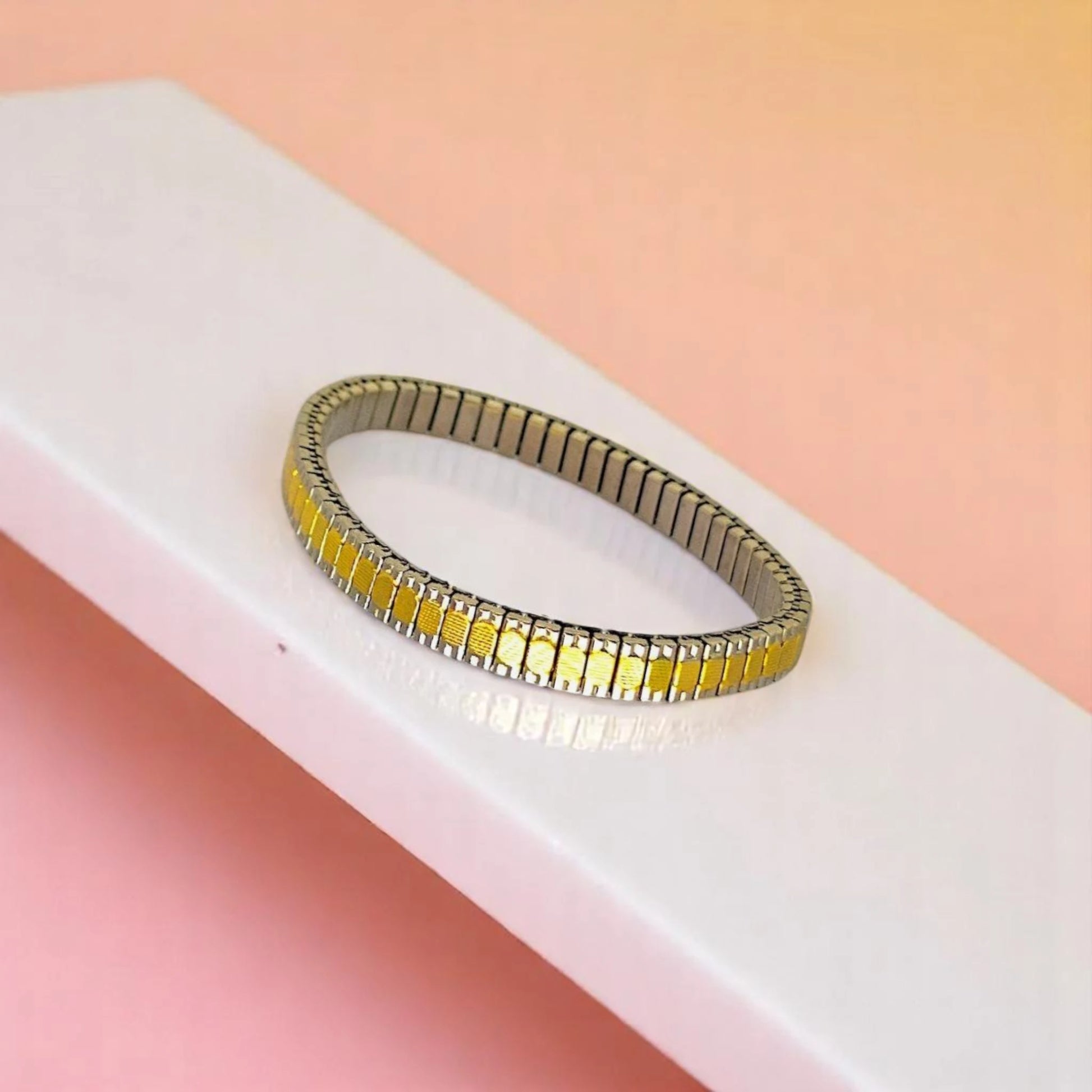 Bracelet on geometric prop with peach color gradient in the background.