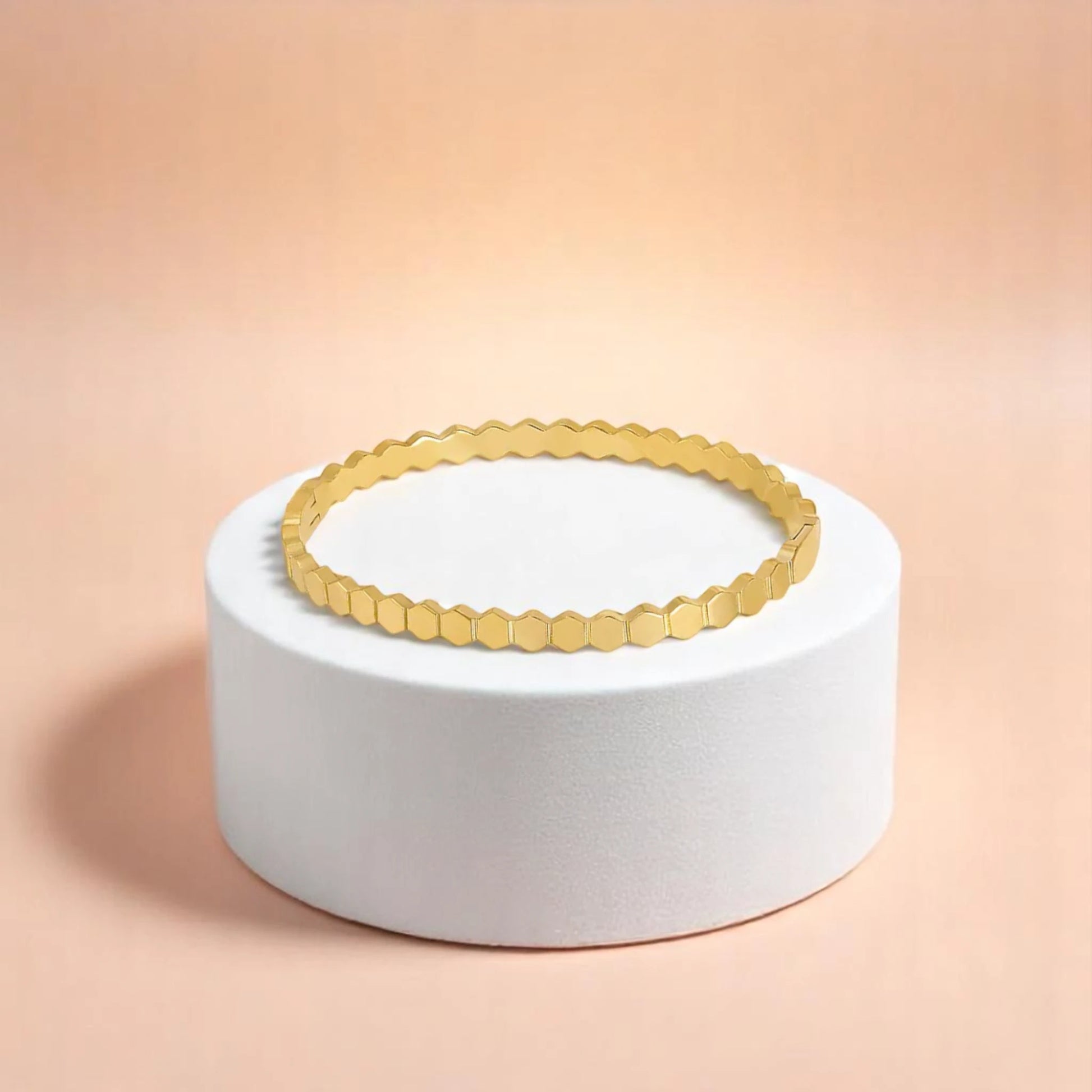 Bracelet on geometric prop with peach color gradient in the background.