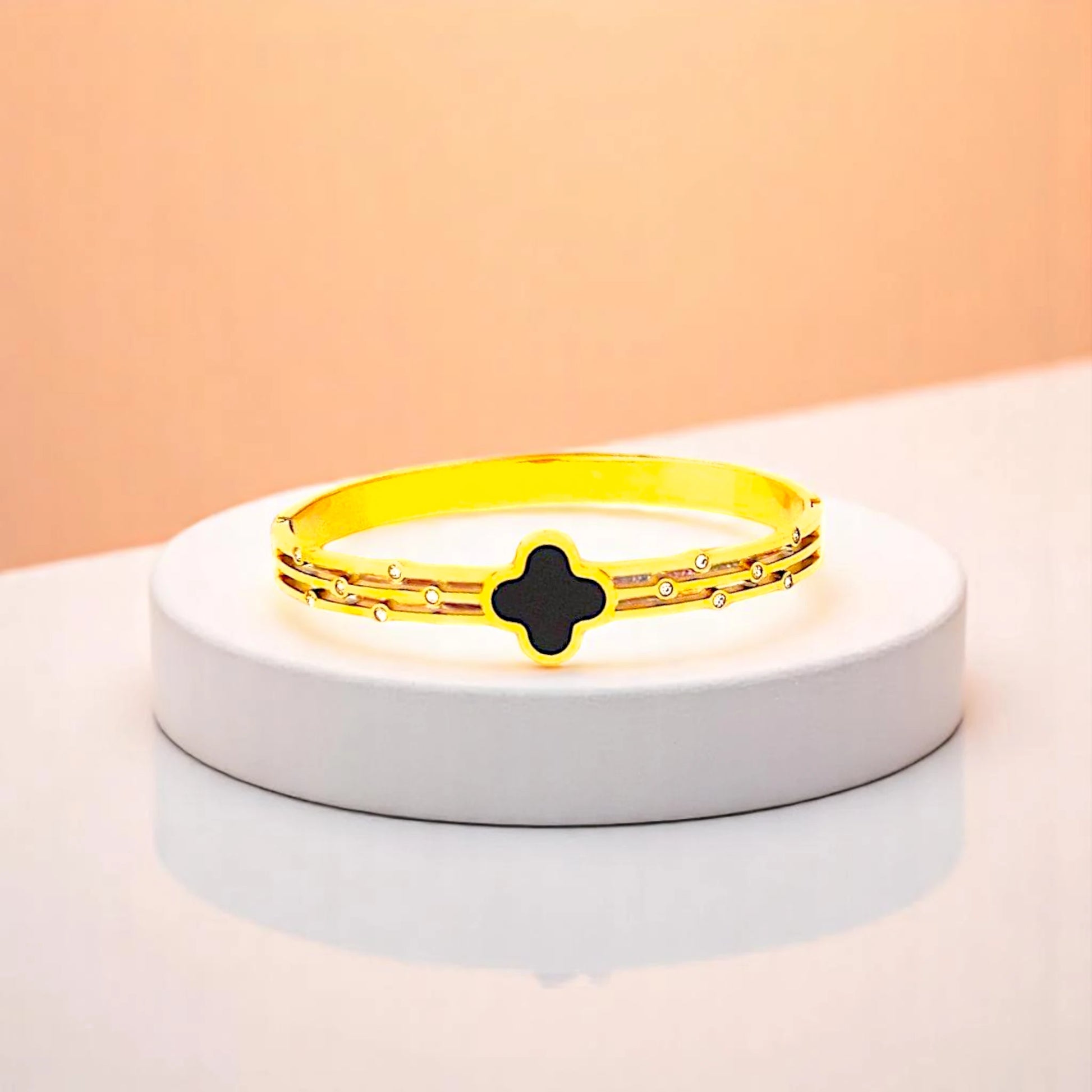 Bracelet on geometric prop with peach color gradient in the background.