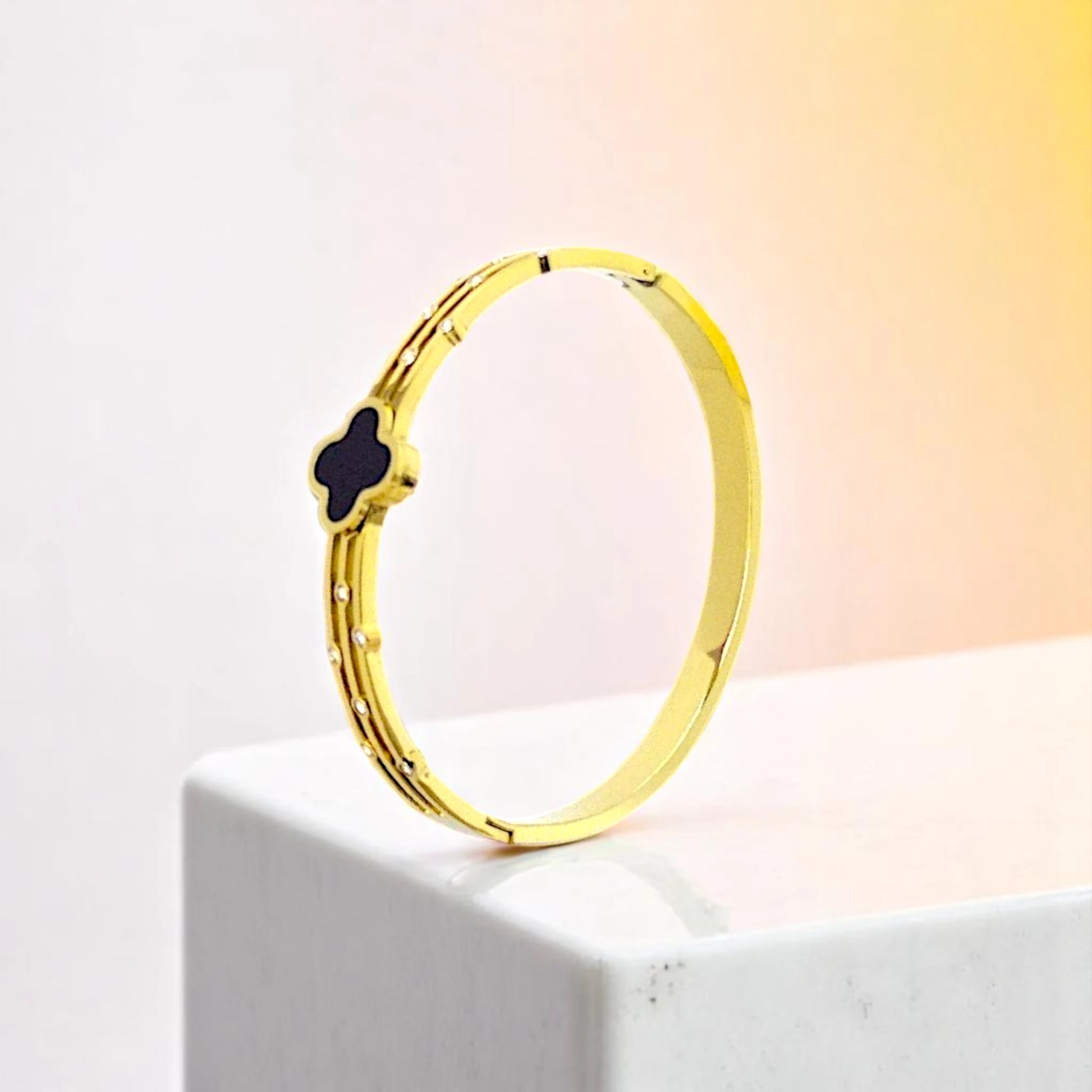 Bracelet on geometric prop with peach color gradient in the background.