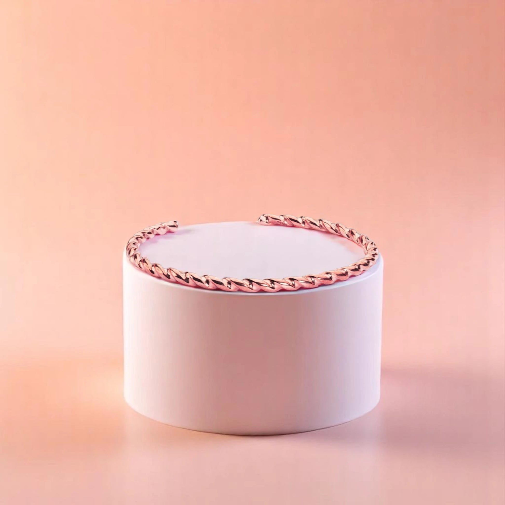 Bracelet on geometric prop with peach color gradient in the background.