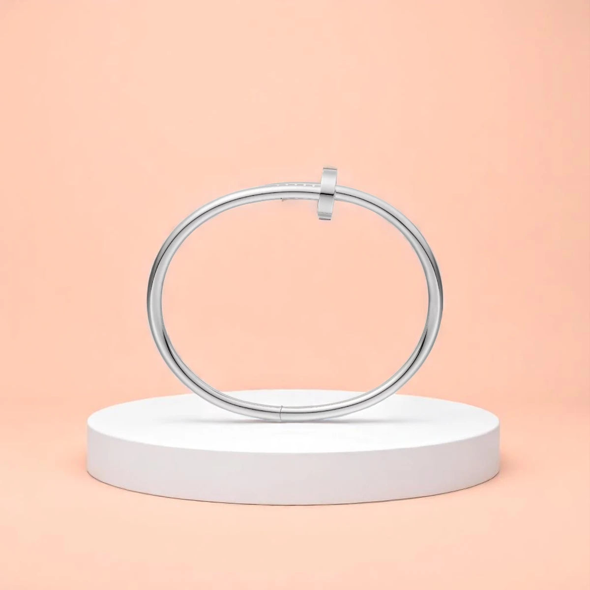 Bracelet displayed on a white pedestal against a soft peach background.