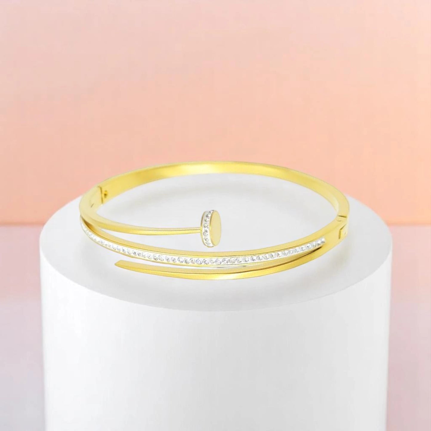 Bracelet on geometric prop with peach color gradient in the background.