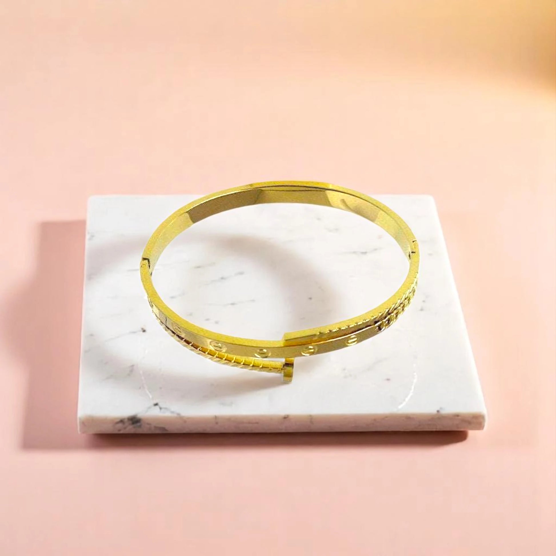 Bracelet on geometric prop with peach color gradient in the background.