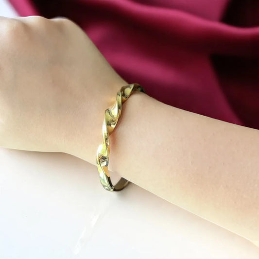 Bracelet worn by a model against a soft maroon cloth background.