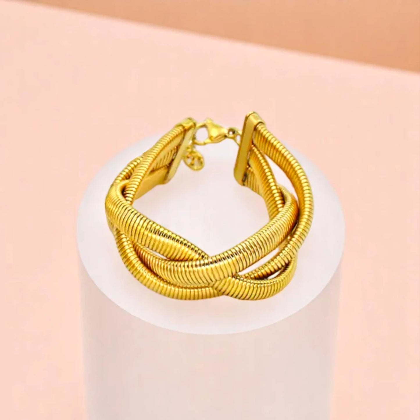 Bracelet on geometric prop with peach color gradient in the background.