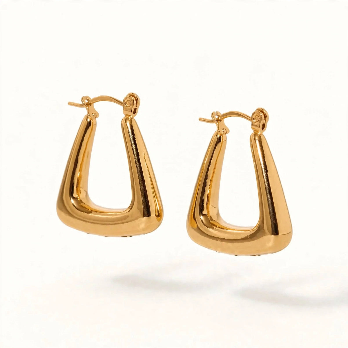 A pair of gold-toned geometric hoop earrings with a polished, tapered triangular design, displayed on a clean white background.