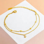 Anklet on a geometric prop with a peach-colored gradient in the background.