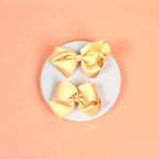 Two beige bows on a white acrylic pedestal with light background