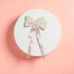 Round white acrylic pedestal with a Beige bow on a light background