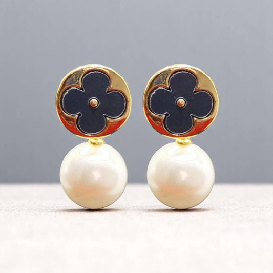 Elegant earrings featuring a gold circular top with a navy flower design, complemented by lustrous white pearl drops.