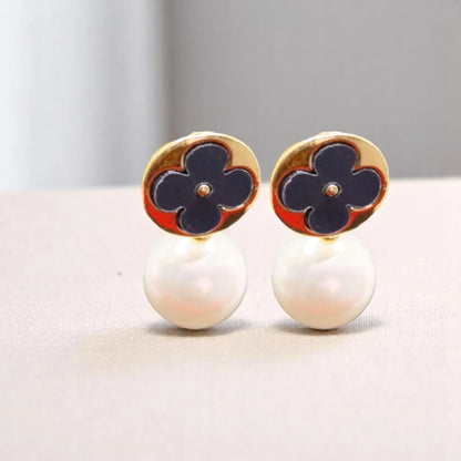 Elegant gold earrings featuring navy blue floral designs atop white pearl drops, combining classic and modern aesthetics.
