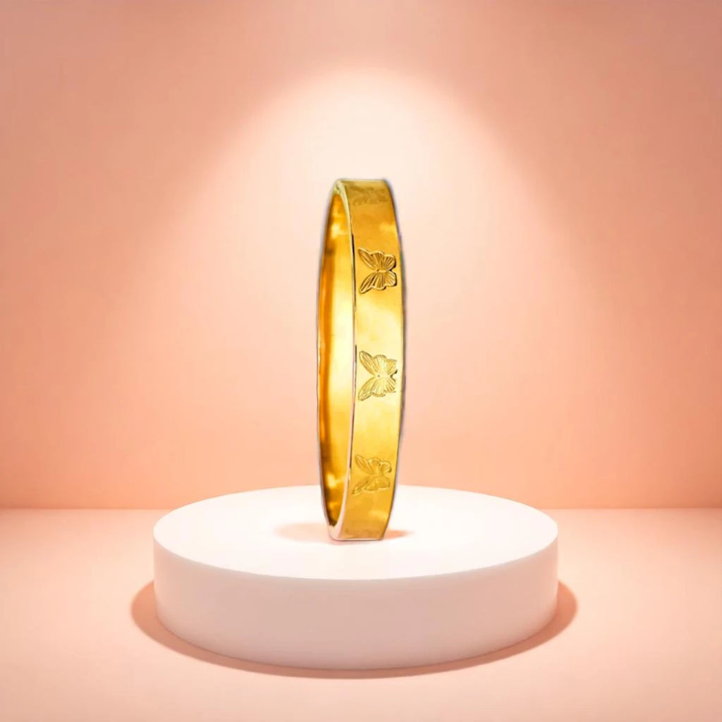 Bracelet displayed on a white pedestal against a soft peach background.