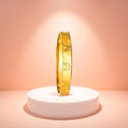 Bracelet displayed on a white pedestal against a soft peach background.