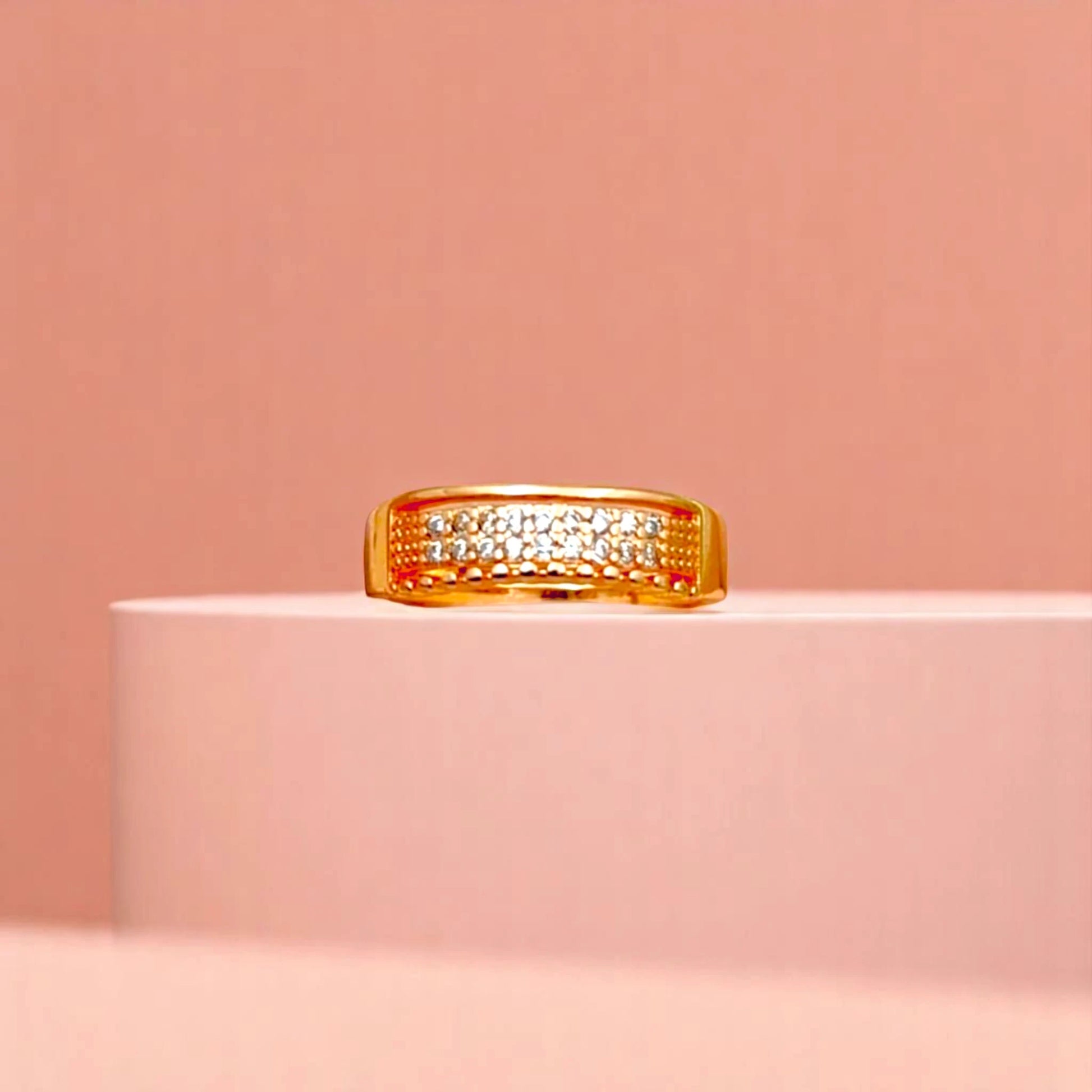 Ring on a white cylindrical geometric prop with a peach color gradient in the background.