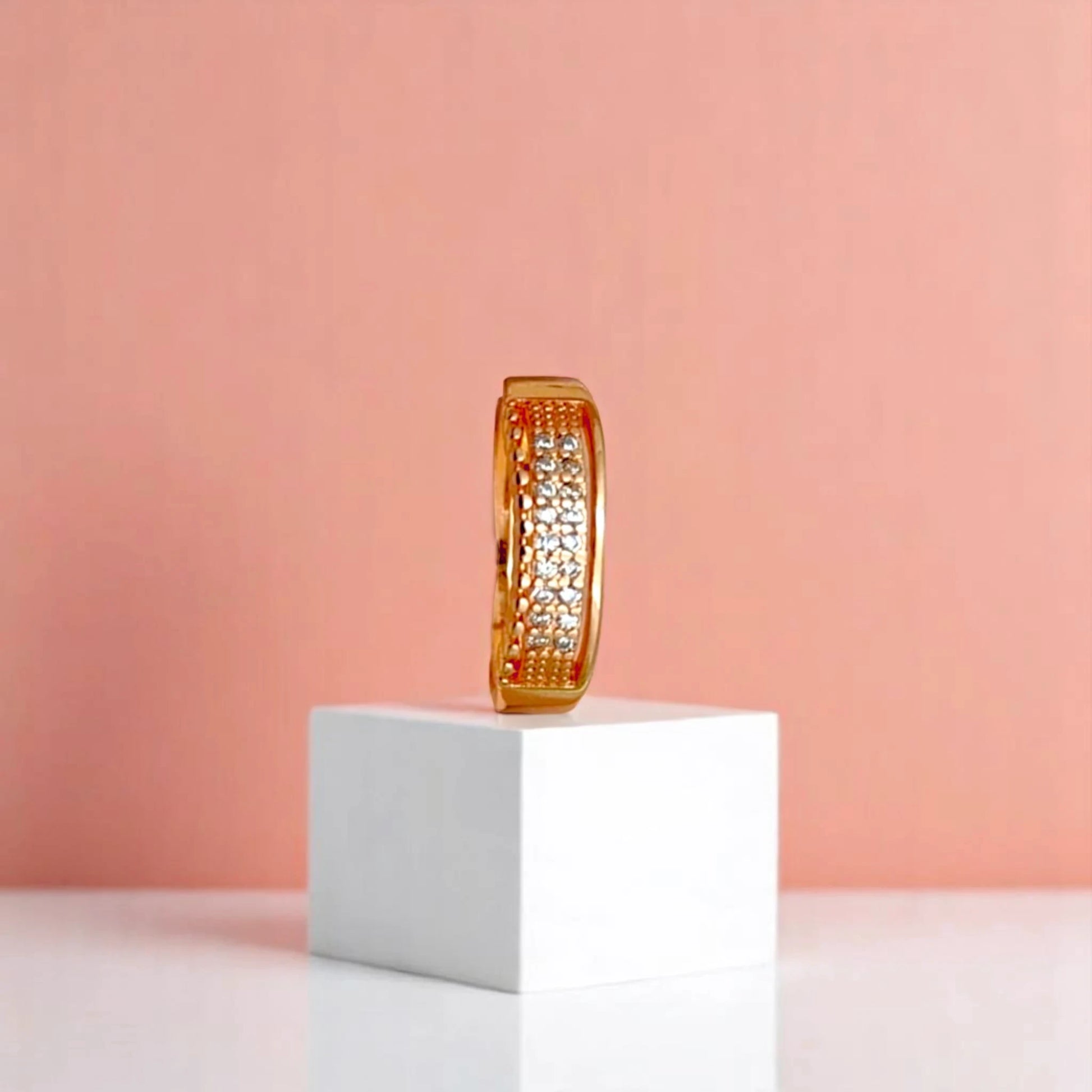 Ring on a white cube geometric prop with a peach color gradient in the background.