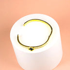 Bracelet displayed on a white pedestal against a soft peach background.