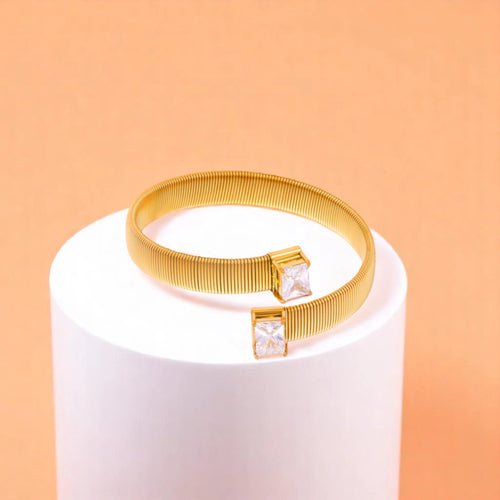 Bracelet on geometric prop with peach color gradient in the background.