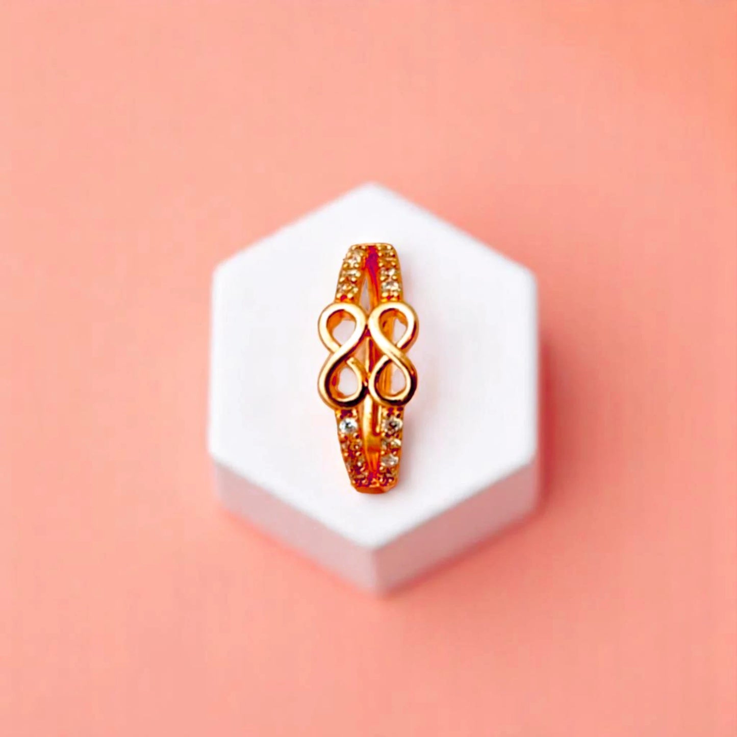 Ring on a white cube geometric prop with a peach color gradient in the background.