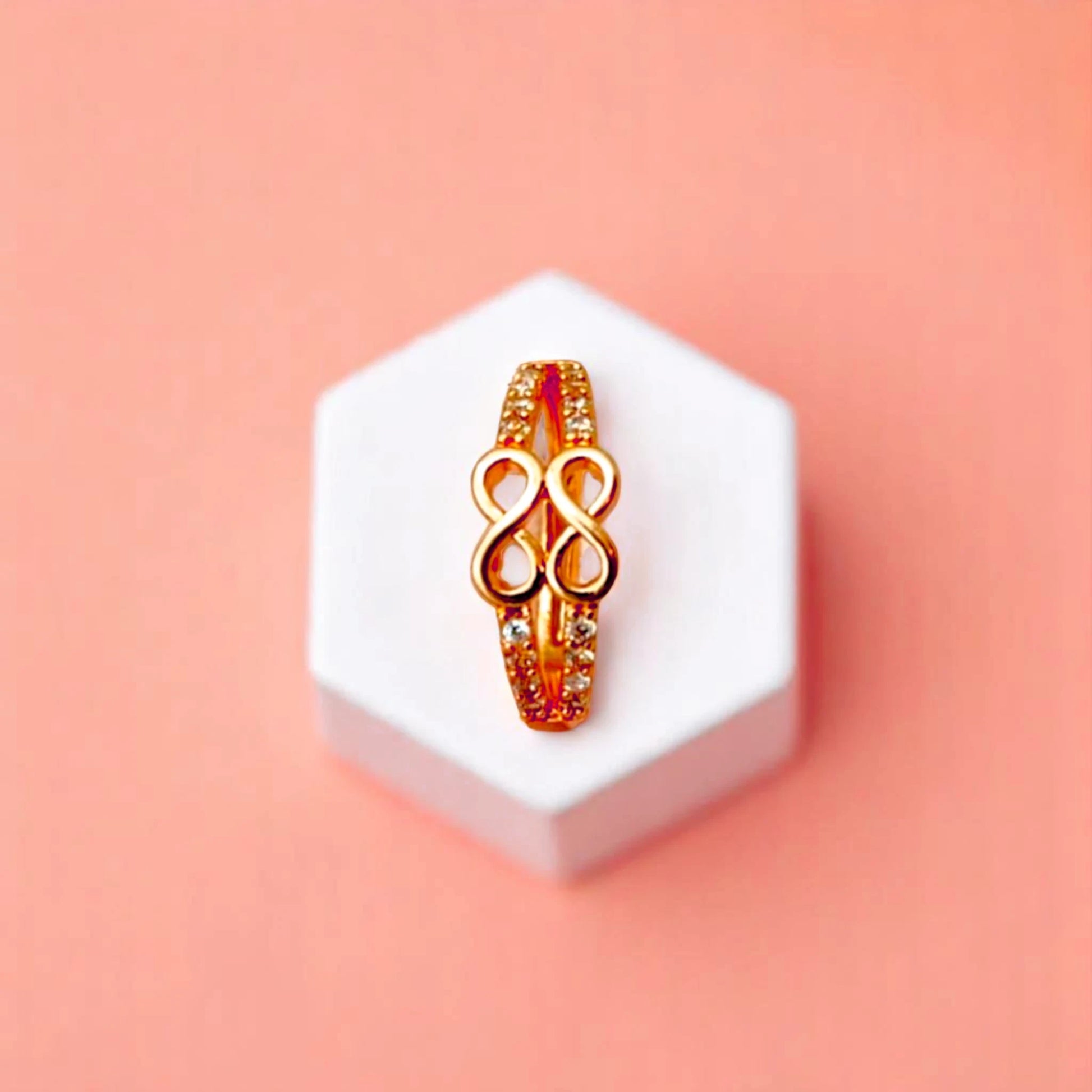 Ring on a white cube geometric prop with a peach color gradient in the background.