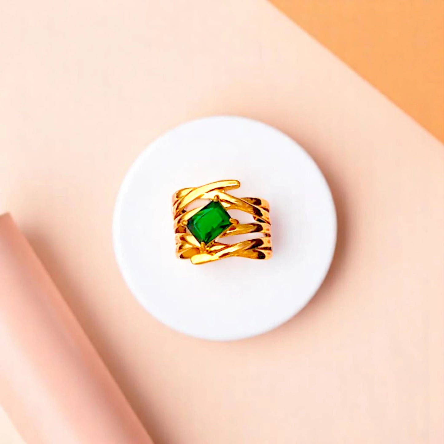 Ring on a white cylindrical geometric prop with a peach color gradient in the background.