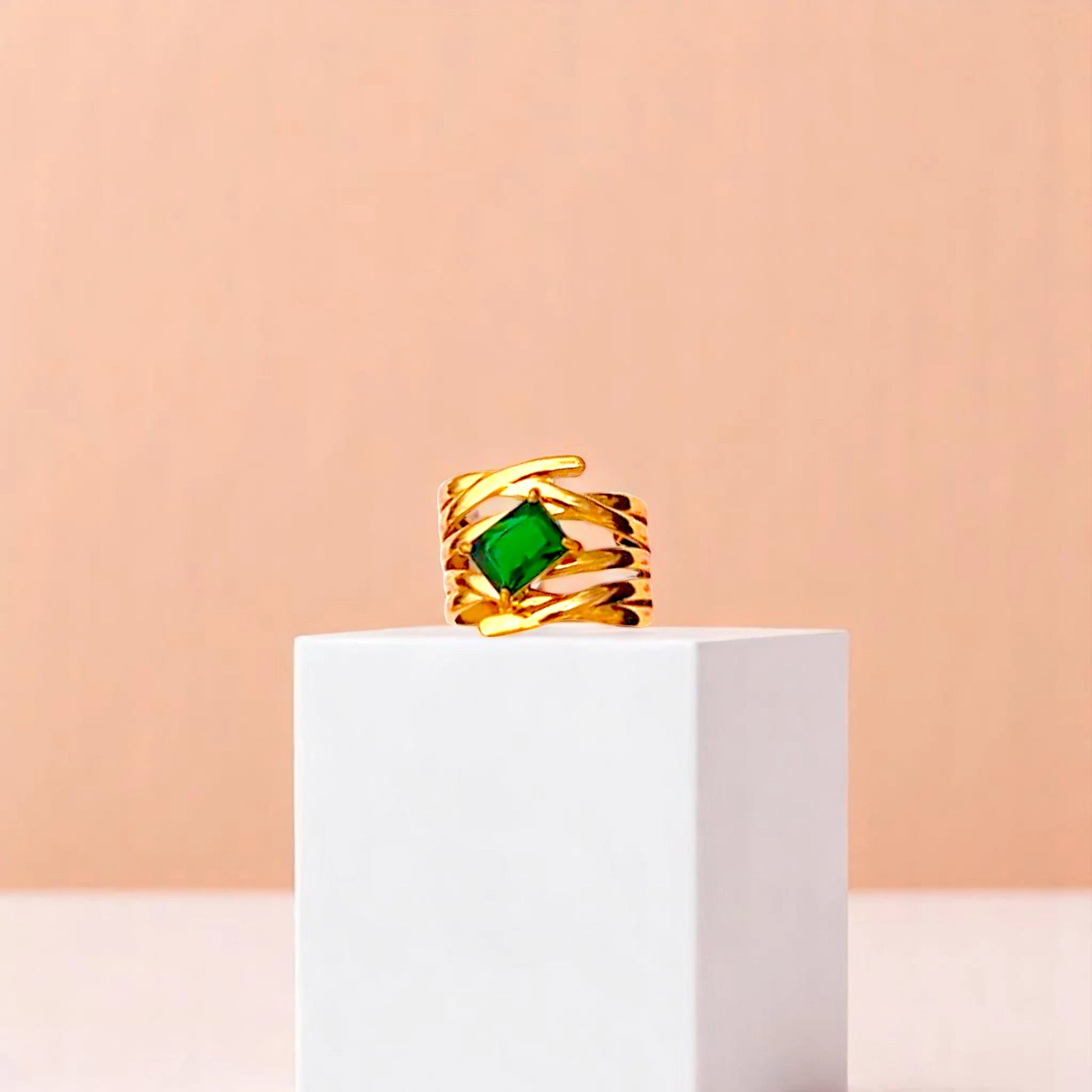 Ring on a white cube geometric prop with a peach color gradient in the background.