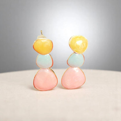 Colorful modern earrings featuring stacked gemstones in yellow, blue, and pink, set in delicate gold edges on a soft surface.