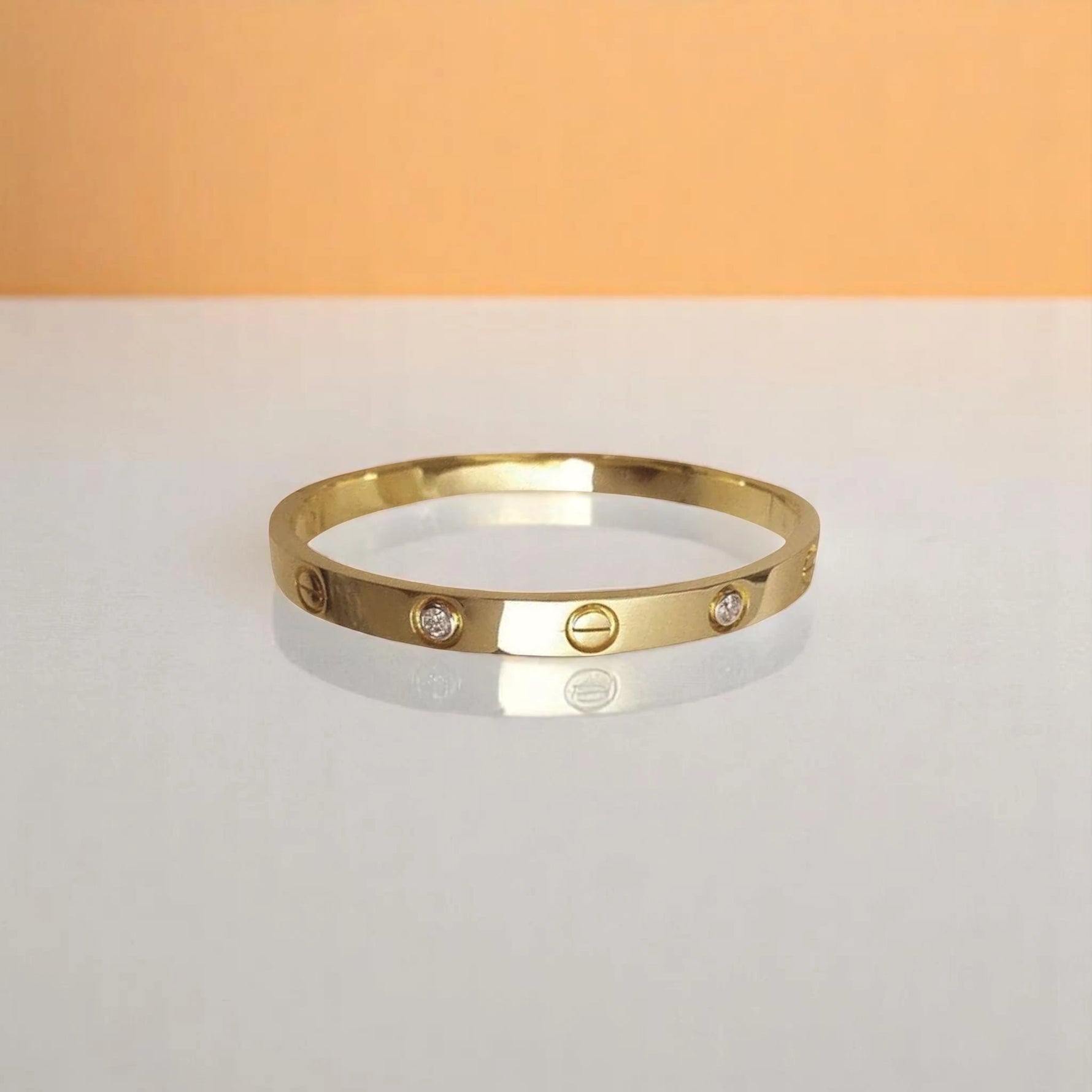 Bracelet on geometric prop with peach color gradient in the background.