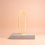 Bracelet displayed on a travertine stone slab with a peach-colored gradient in the background.