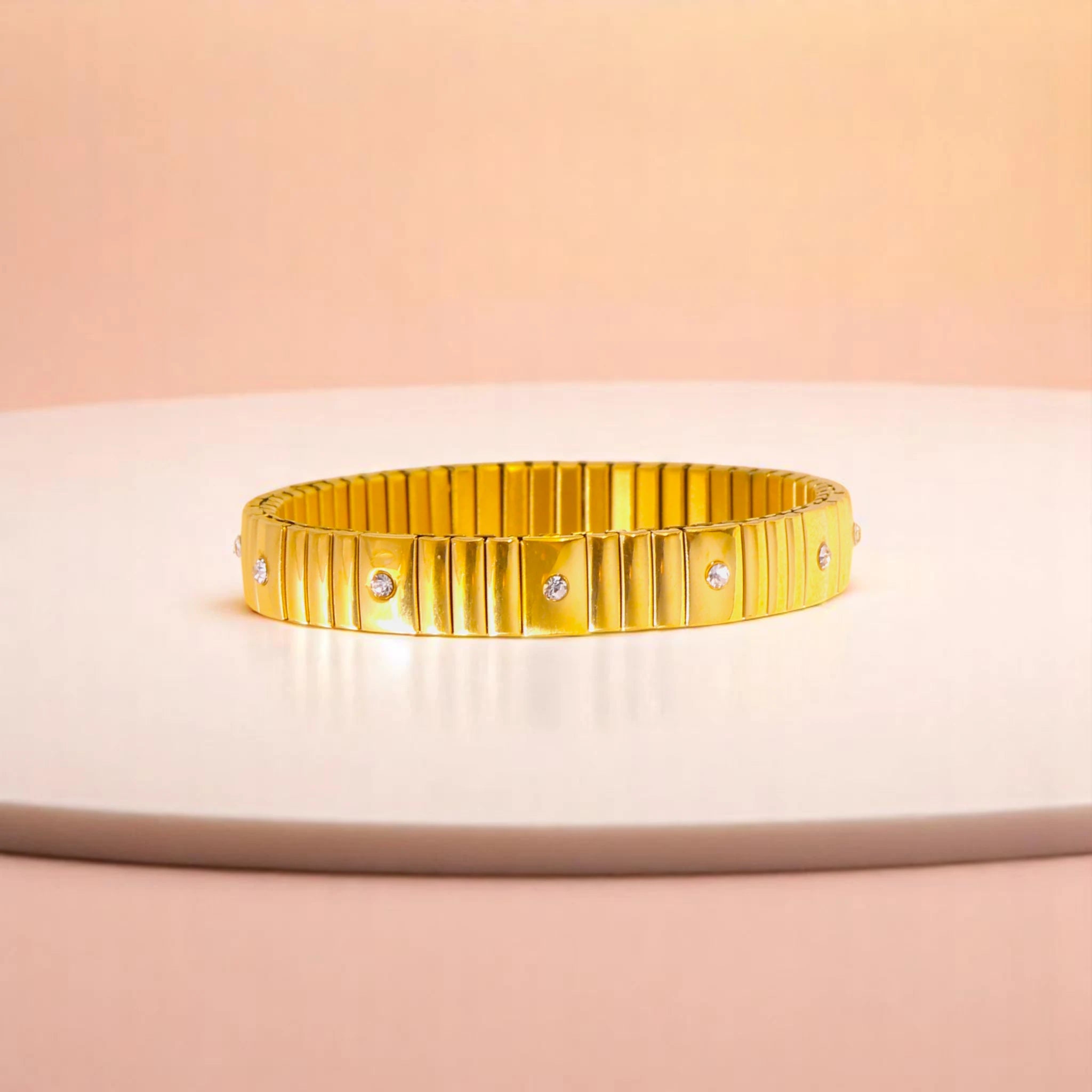 Bracelet on geometric prop with peach color gradient in the background.