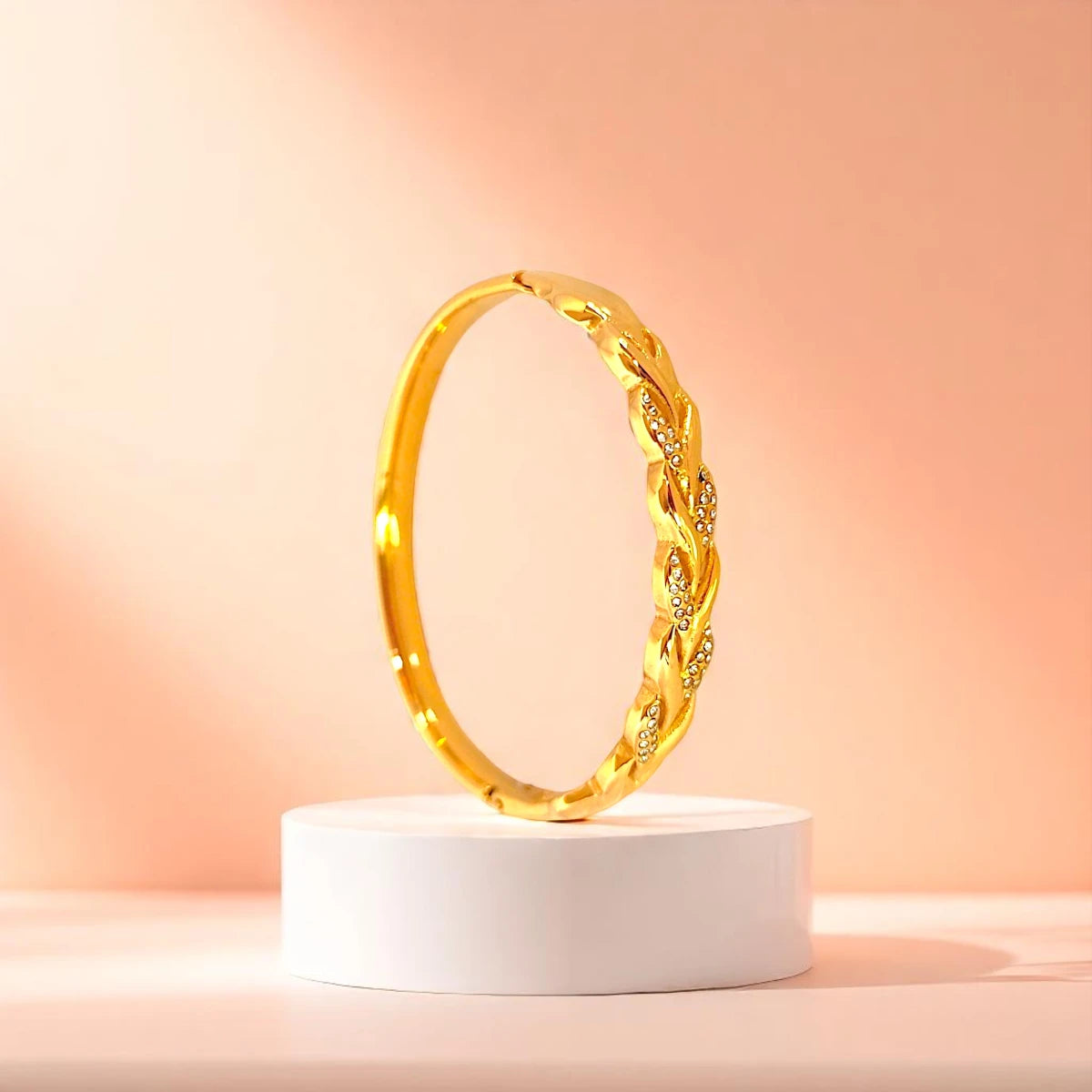 Bracelet displayed on a white pedestal against a soft peach background.