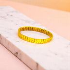 Bracelet on geometric prop with peach color gradient in the background.