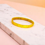 Bracelet on geometric prop with peach color gradient in the background.