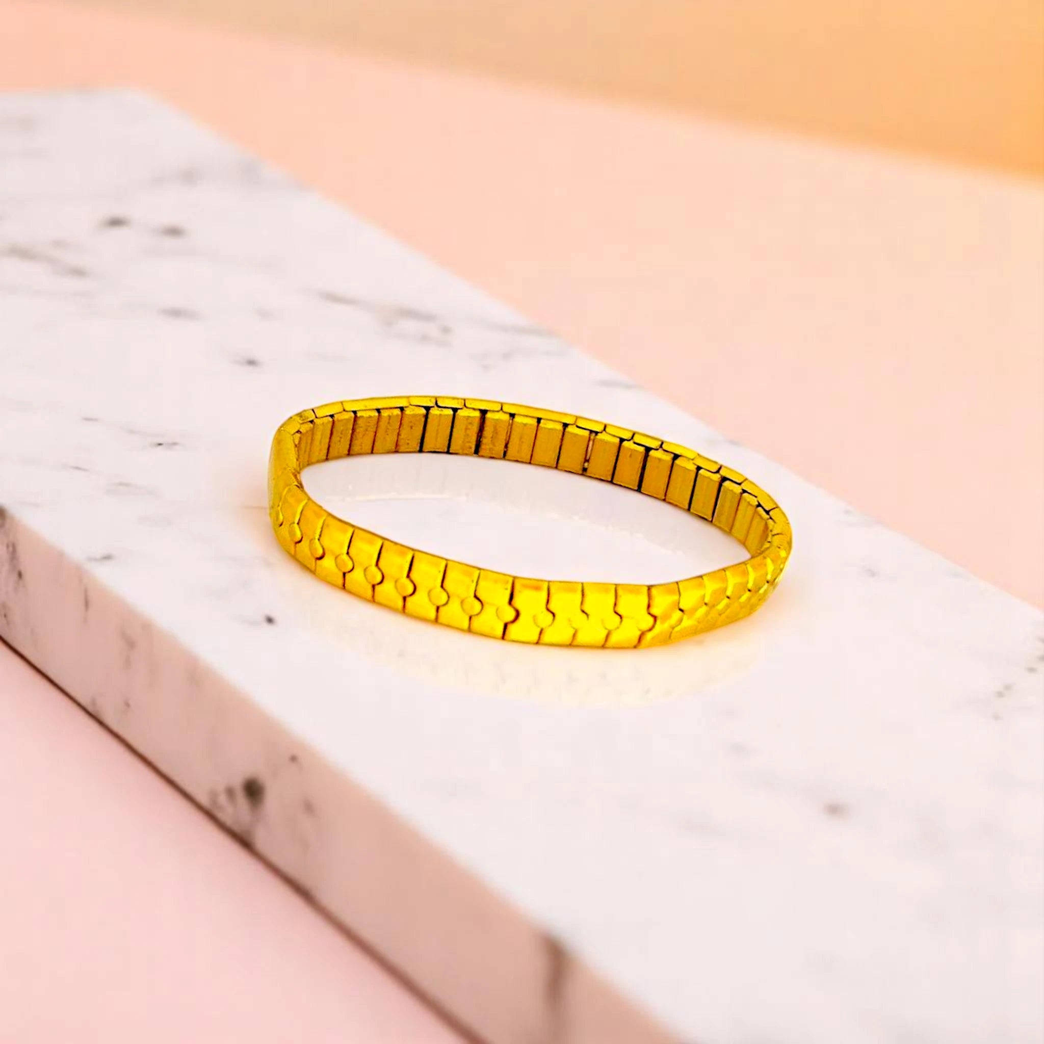 Bracelet on geometric prop with peach color gradient in the background.