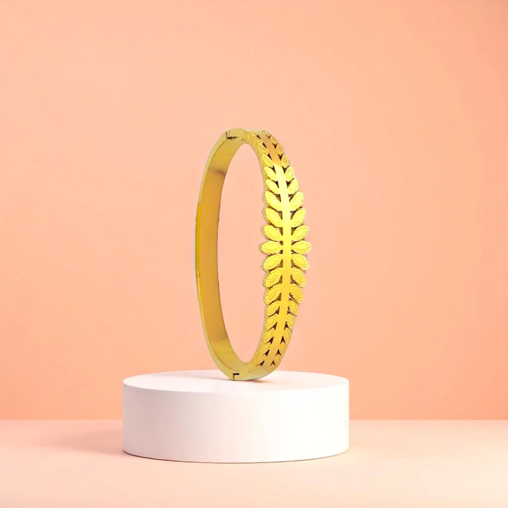 Bracelet displayed on a white pedestal against a soft peach background.