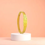 Bracelet displayed on a white pedestal against a soft peach background.