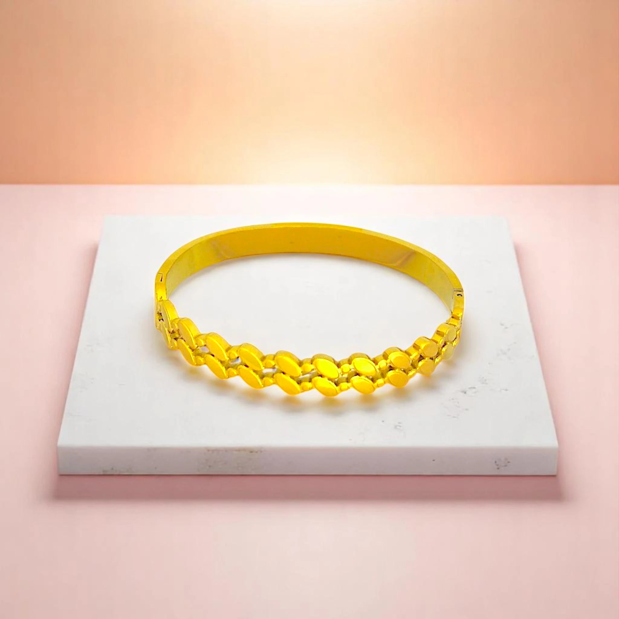 Bracelet on geometric prop with peach color gradient in the background.